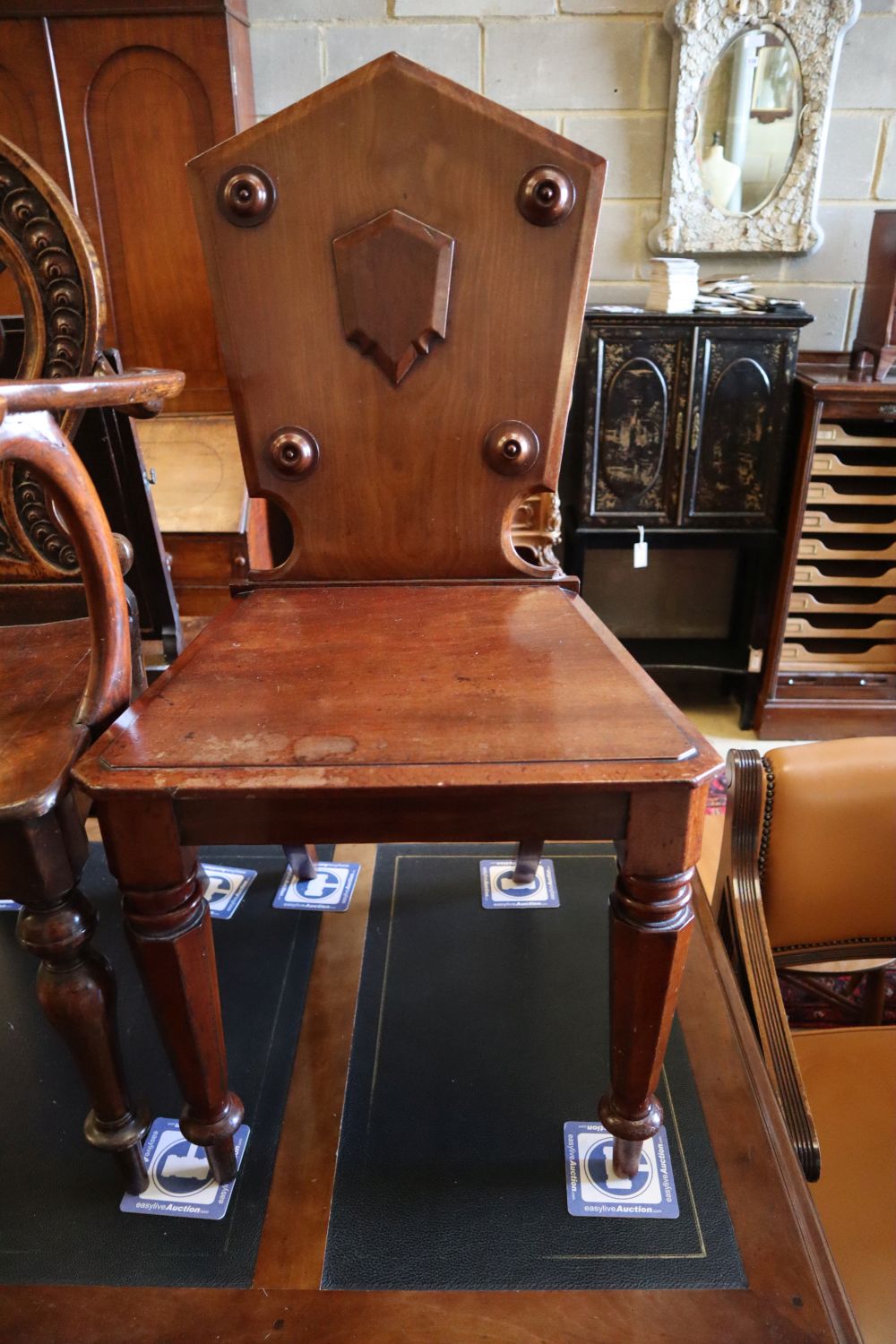 A 19th century carved oak hall elbow chair, together with two similar mahogany hall chairs